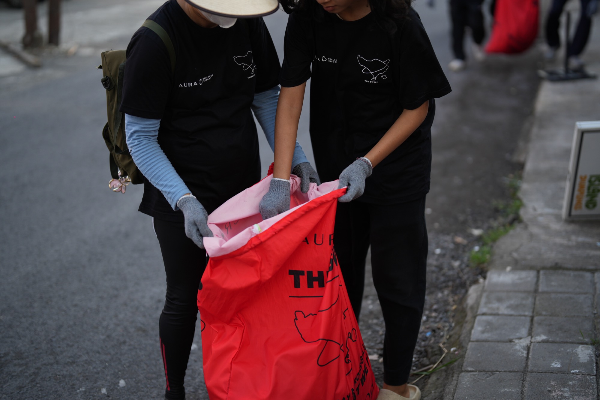 Volunteers filling a red The Sweep bag on the street